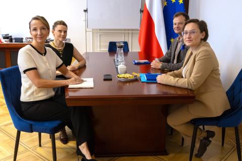 Cztery osoby siedzą przy stole w gabinecie i pozują do wspólnego zdjęcia