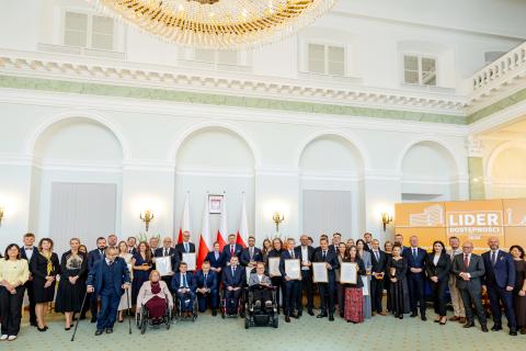 Kilkadziesiąt osób pozuje na stojąco do wspólnego zdjęcia w zabytkowym pomieszczeniu