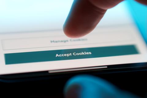 Ekran smartfona z palcem nad przyciskiem z napisem "Accept Cookies"