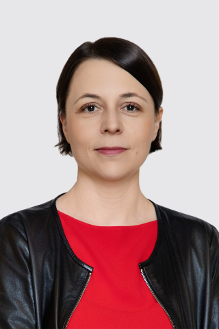 Portret Anny Błaszczak-Banasiak - lekko uśmiechnięta kobieta z krótkimi, czarnymi włosami na neutralnym tle