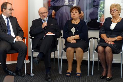 zdjęcie: dwaj mężczyźni i dwie kobiety siedzą na krzesłach, mężczyzna drugi od lewej mówi do mikrofonu