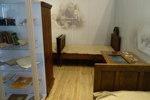 Zdjęcie: sala muzealna z prostymi sprzętami domowymi: łóżkiem i szafą