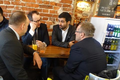 zdjęcie: przy małym stoliku w kawiarni siedzi czterech mężczyzn w garniturach