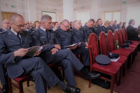 zdjęcie: kilkunastu mężczyzn w granatowych mundurach siedzi i przeglada publikacje