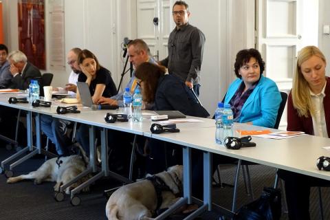 Zdjęcie: ludzie przy stole konferencyjnym, pod stołem - pies-przewodnik osoby niewidomej