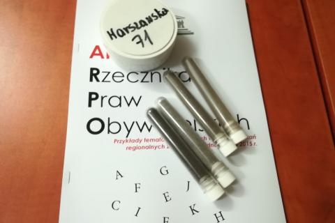 Fiolki z szarym pyłem na publikacji "Alfabet RPO"