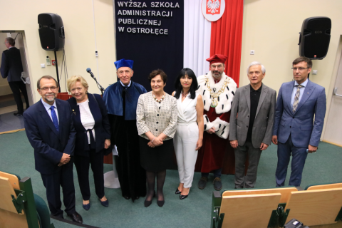 Ludzie pozują do zdjęcia na tle napisu Wyższa Szkoła Administracji Publicznej w Ostrołęce