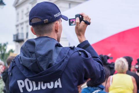 Policjant filmujący biało-czerwoną flagę