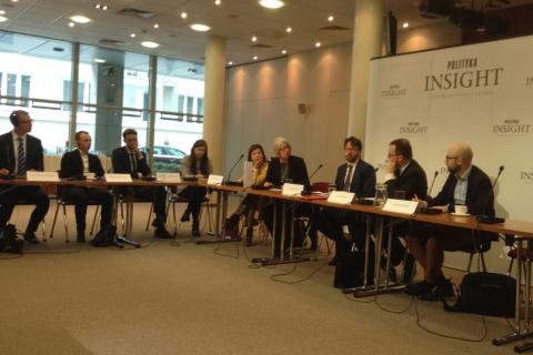 Ludzie siedzą wokół stołu, kobieta zadaje pytanie