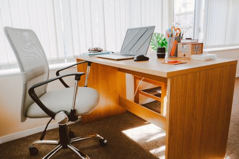 Biuro - fotel, biurko z laptopem i myszką materiałami biurowymi