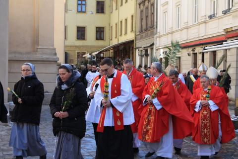 Procesja - zakonnice i księża w czerwonych szatach niosą palmy